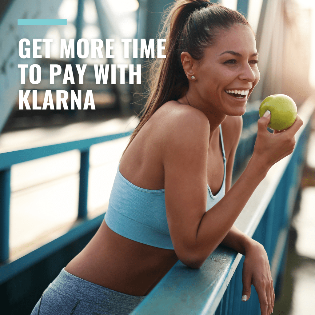 An attractive smiling woman in yoga clothes taking a break and eating a green apple, with text that says 'Get More Time To Pay with Klarna
